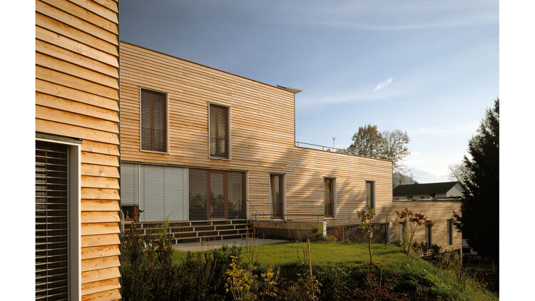 © Eduard Hueber, Archphoto Wohngebäude mit Holzfassade und umliegender Begrünung