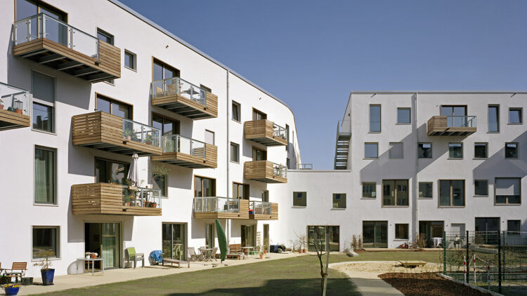 © Oliver Heissner Begrünter Innenhof mit umliegenden Gebäuden mit Holzbalkonen