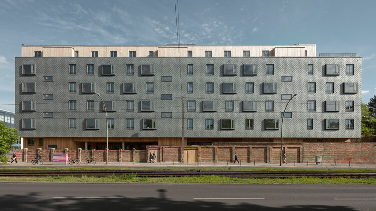 © Jan Bitter Zeilenbau hinter einer Mauer an einer Straße