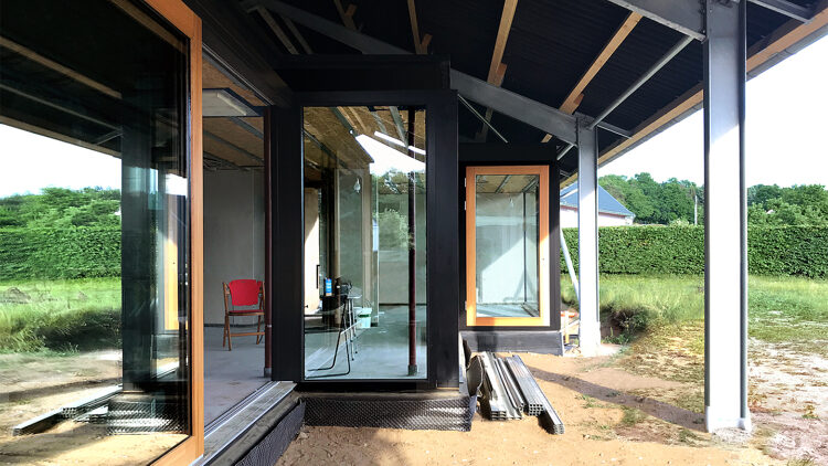 © SUMMACUMFEMMER Außenansicht eines schwarzen Hauses mit bodentiefen Fenstern