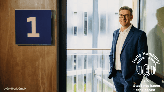 Podcast-Gast Christopher Conrads am offenen Fenster, an der Wand prangt eine große Eins