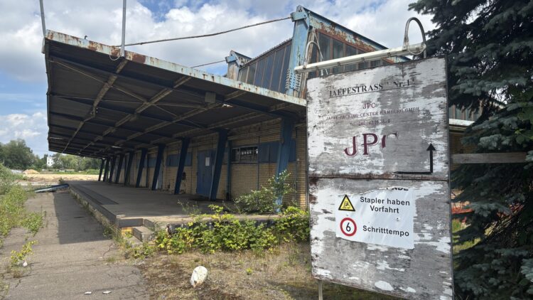 © IBA Hamburg / Arne von Maydell Verlassene Lagerhalle mit rostigem Vordach und verwittertem Firmenschild „JPC Jaffe-Packing-Center Hamburg GmbH“ sowie Warnhinweisen zu Staplerverkehr