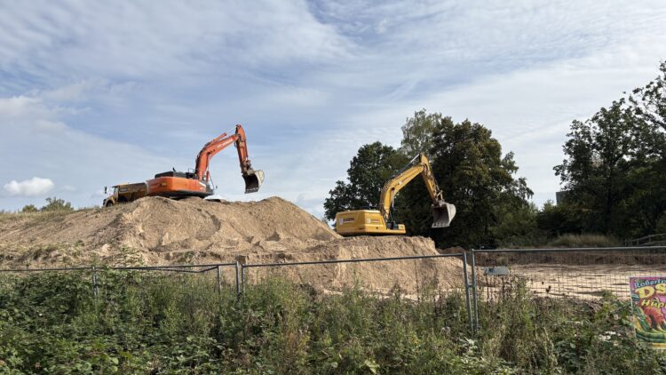 © IBA Hamburg / Jakub Oblocki Zwei Bagger stehen auf einem großen Sandhügel; ein Bagger lädt Sand mit seiner Schaufel in einen gelben Dumper.
