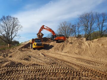 © IBA Hamburg / Arne von Maydell Ein Bagger lädt Sand in einen Muldenkipper auf der Baustelle.