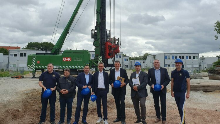 © IBA Hamburg / Arne von Maydell Viele Menschen posieren auf einer Baustelle vor Baumaschinen