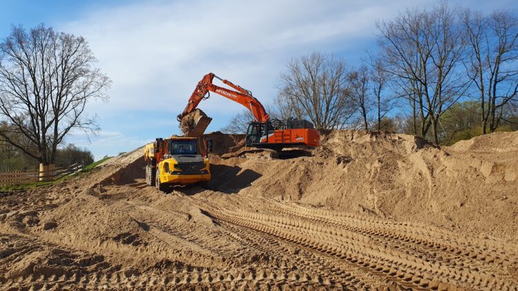 © IBA Hamburg / Arne von Maydell Ein Bagger lädt Sand in einen Muldenkipper auf der Baustelle.