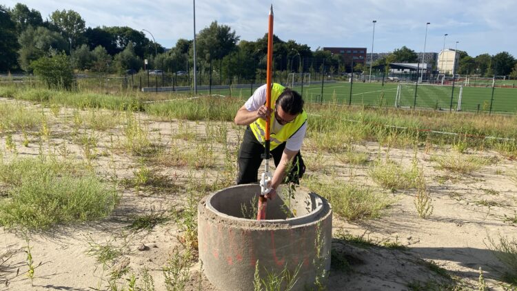 © IBA Hamburg Ein Vermessungsingenieur richtet einen Prismenstab auf einem Setzungspegel aus.