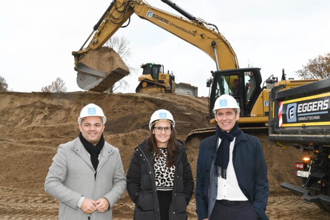 © IBA Hamburg / Andreas Fromm Ralf Neubauer, Karen Pein und Kay Gätgens auf der Baustelle in Wilhelmsburg, im Hintergrund sind Baumaschinen zu sehen