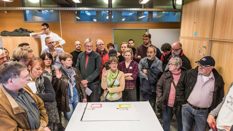 Menschen stehen um einen Tisch herum