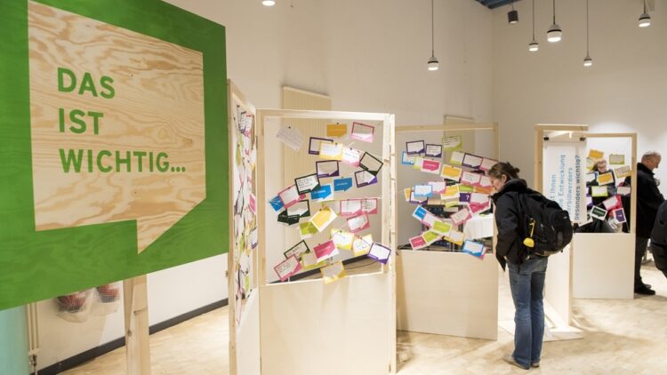 Eine Person steht vor einer Ausstellungswand mit Notizen