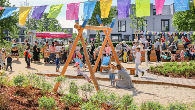© IBA Hamburg / Andreas Bock Mit bunter Wimpelkette dekorierter Spielplatz mit Personen