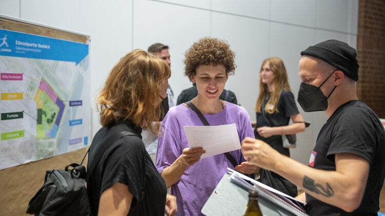 © IBA Hamburg / Bente Stachowske Menschen stehen vor einer Stellwand und unterhalten sich